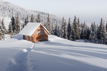 Fantastic winter landscape with wooden house in snowy mountains. Christmas holiday concept. Carpathians mountain, Ukraine, Europe