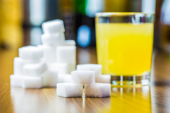 ein Glas mit Saft und viel W&uuml;rfelzucker sind auf einem Tisch