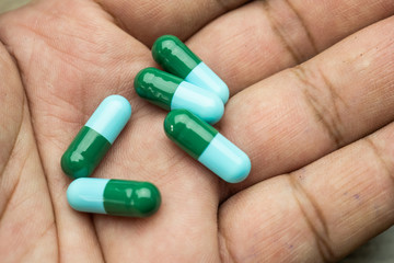 drug capsule antibiotic in hand male wood table background