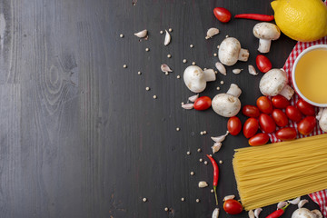 Spaghetti ingredients on black wooden desk, top view.
