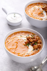 Carrot pumpkin soup with spicy chickpeas and sesame seeds on gray stone background copy space