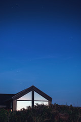Midnight sky with a vacation house and light reflection the sunset in the triangle windows