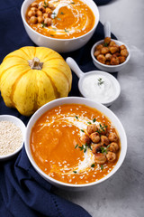 Fototapeta na wymiar Carrot pumpkin soup with spicy chickpeas and sesame seeds on gray stone background copy space