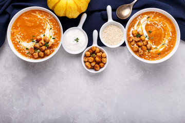 Carrot pumpkin soup with spicy chickpeas and sesame seeds on gray stone background copy space