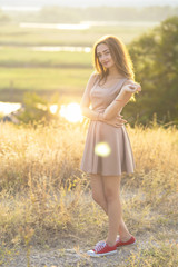 Fototapeta na wymiar beautiful dreamy girl walking in a field in a dress at sunset, a young woman enjoying summer nature