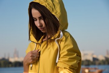 Portrait of confident serious woman under yellow hood over blue sky background © antgor