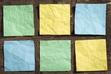 Six crumpled blank note papers in different colors on a wooden surface