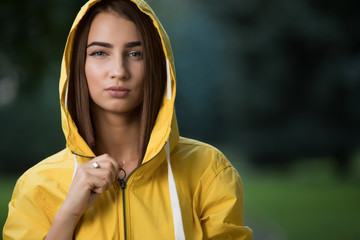 Woman wear yellow raincoat with hood in park © antgor