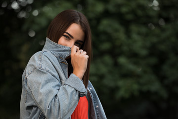 Woman hiding her face behind a denim jacket