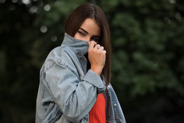 Woman hiding her face behind a denim jacket in a park