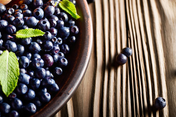 Clay plate full of Ripe organic blueberries on wooden table