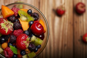 Top view of assorted fruits in glass bowl on kitchen wooden table