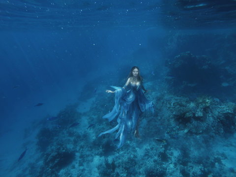 a magical fairy mermaid in a blue flying light dress floats on the ocean floor, sea queen and jellyfish, a halloween image, a photo under water in the red sea, a water nymph or a drowned woman. art