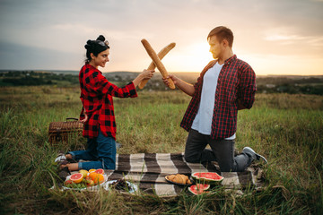 Playful couple fight on loaves, picnic in field © Nomad_Soul