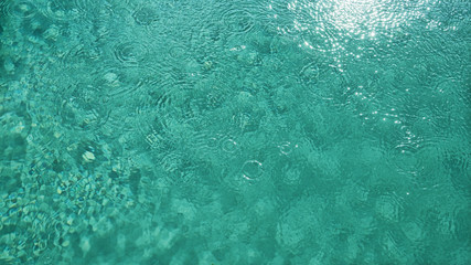 Kräuselungen von Wassertropfen, Kreise auf Türkis blaue Wasser, Pool, See, Spiegelung der Sonne, abstrakter Hintergrund Muster verwischt.mit Raum für Text.