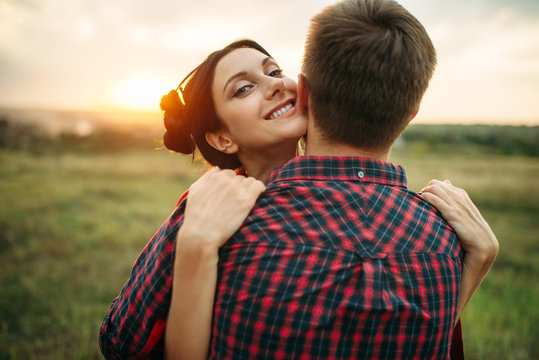 Love couple hugs on the meadow at sunset