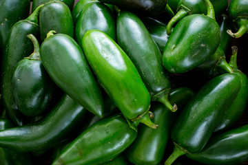 Bunch of Jalapeño peppers on a kitchen counter waiting to be sliced up with a knife by the chef.