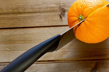 Knife slicing through an orange of the kitchen table before breakfast