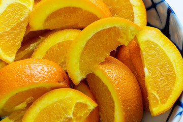 Orange slices in a white and blue bowl waiting to be eaten on a white table.