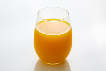 Fresh squeezed orange juice right off a tree into the glass on white kitchen table ready for breakfast in the morning