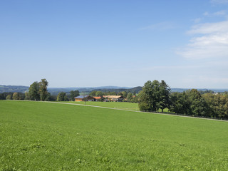 Fototapeta na wymiar Paysages de Bavière. Vues sur les collines, prairies verdoyantes et pâturages autour du village de Hundham dans la vallée du Leitzach au pied du Schwarzenberg.