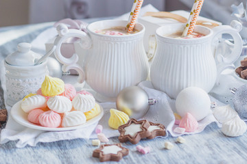 Cups of cacao with marshmallow, meringues and different Christmas decorations