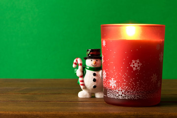 Fun toy snowman and a Christmas candle on a wooden table. The concept of Christmas.Empty text space