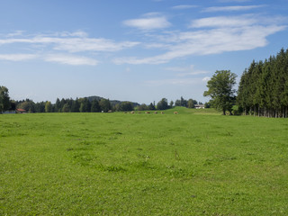 Fototapeta na wymiar Paysages champêtres de Bavière. Vues sur les collines, prairies verdoyantes et pâturages autour du village de Hundham dans la vallée du Leitzach au pied du Schwarzenberg.