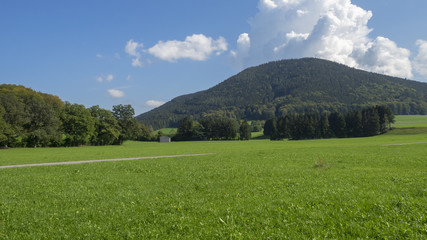 Fototapeta na wymiar Paysages champêtres de Bavière. Vues sur les collines, prairies verdoyantes et pâturages autour du village de Hundham dans la vallée du Leitzach au pied du Schwarzenberg.