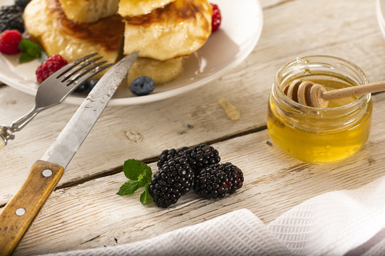 Pancakes with forest fruits berries on white table.