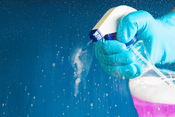 Hand in a blue glove holding a washer - washing the glass