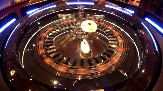 Aerial view of Roulette Wheel spinning under glass sphere with reflections of the overhead lights
