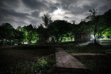 Fototapeta premium Mountain night landscape of building at forest at night with moon or vintage country house at night with clouds and stars. Summer night.
