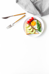 Healthy hearty breakfast. Fried eggs with vegetables near toast with avocado on white background top view copy space