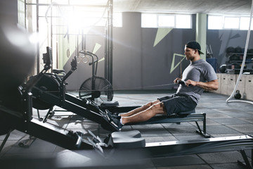 Cardio Training. Sports Man Exercising On Rowing Machine At Gym