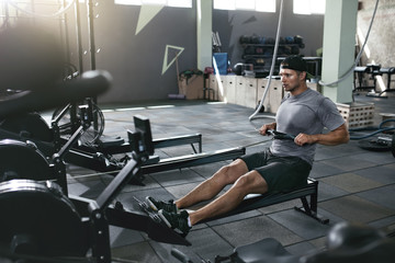 Functional Training. Man Doing Exercise On Rowing Machine At Gym