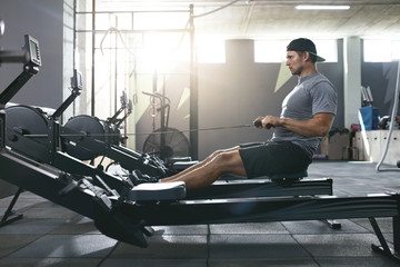 Functional Training. Man Doing Exercise On Rowing Machine At Gym