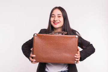Happy brunette young woman with red lips holding retro suitcase on white background