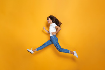 Fototapeta na wymiar Full length portrait of a joyful girl with long dark hair jumping