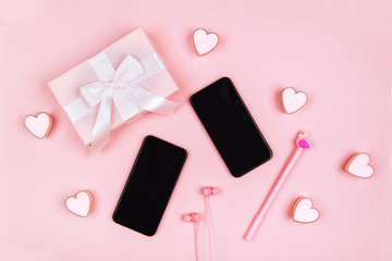 Smartphone, gifts, headphones and female accessories on pink background