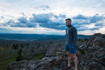 Travel, freedom and tourism concept - man standing on top of cliff in summer beauty evening in Altai mountains