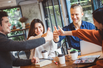 Group of young business people discussing and meeting at coffee cafe, laughing with happy