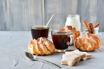  two cups of black coffee in transparent cups, milk and round eclairs with cream filling 