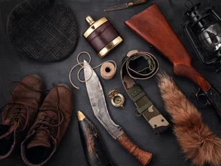 Photo sur Plexiglas Chasser Mise à plat avec accessoires de chasse sur fond gris : vieilles bottes, chapeau, fusil, couteaux, corde, ceinture, queue de renard.