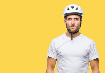 Young handsome man wearing cyclist safety helmet over isolated background with serious expression on face. Simple and natural looking at the camera.