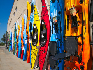 Colorful fiberglass kayaks on display outside sporting goods store in lake country of northern...