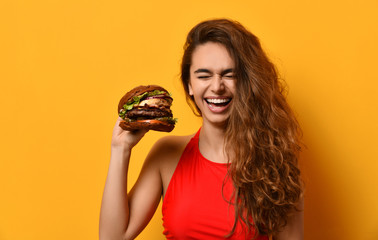Woman hold big barbecue burger sandwich with hungry mouth happy screaming laughing on yellow...