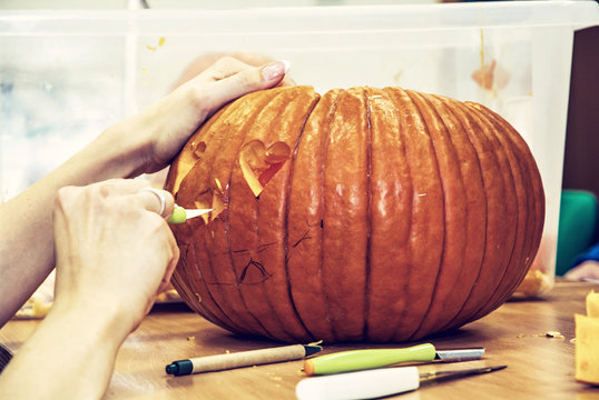 Women's hands who cuts jack-o-lantern with knife