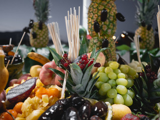 Assorted fruits in table. Outside night closeup. Grape, pineapple, orange, grapefruit, banana, date.