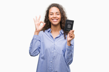 Young hispanic woman holding passport of Italy doing ok sign with fingers, excellent symbol